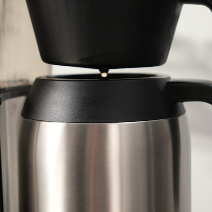 Close-up of a stainless steel thermos with black lid